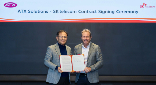 하민용(왼쪽) SKT CDO와 로저 데이비스 에이티엑스 창업자 겸 디렉터가 유통 계약 체결 후 기념사진을 찍고 있다. SKT 제공